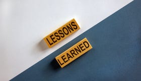 Wooden blocks with text `lessons learned` on beautiful white and blue background. Business concept