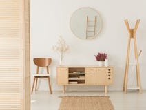 Wooden cabinet with flowers between stylish brown chair and wooden hanger royalty free stock photo Wooden cabinet with flowers between stylish brown chair and wooden hanger royalty free stock photo