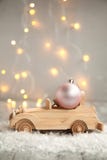 Wooden Car With Christmas Ball On A Wooden Gray Background And Lights From The Garland. Christmas Concept Stock Image