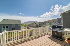 Wooden deck of a house with a barbecue grill and a view of residential houses and mountain