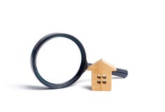Wooden house and magnifying glass on a white background. Buying and selling real estate, building new buildings, offices and homes