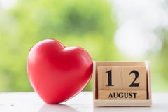 Wooden square block number 12 August with a red heart shape ball on wooden floor royalty free stock image Wooden square block number 12 August with a red heart shape ball on wooden floor royalty free stock image