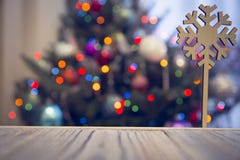 A wooden snowflake on a wooden table against decorated Christmas tree royalty free stock photos A wooden snowflake on a wooden table against decorated Christmas tree royalty free stock photos