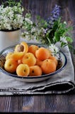 On a wooden table on a platter of fresh apricots with bones, decorated with flowers stock photo On a wooden table on a platter of fresh apricots with bones, decorated with flowers stock photo