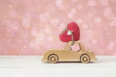 Wooden toy car with heart on the roof on a pink background. Place for text. stock photo Wooden toy car with heart on the roof on a pink background. Place for text. stock photo