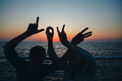 Word love silhouette of two young people making love shape of hands at the beach at sunrise sky summer time, seashore summer beach Stock Photo Word love silhouette of two young people making love shape of hands at the beach at sunrise sky summer time, seashore summer beach Stock Photo
