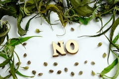 The word NO is laid out of wooden letters in the center of the frame from the dry leaves and the grains of the cannabis. stock images The word NO is laid out of wooden letters in the center of the frame from the dry leaves and the grains of the cannabis. stock images