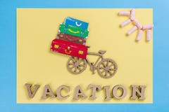 Word vacation abstract wooden letters. Background blue yellow, image of heap of suitcases on bicycle Stock Photo Word vacation abstract wooden letters. Background blue yellow, image of heap of suitcases on bicycle Stock Photo