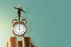Work Life Balance for Time and Money Concept. Excited Businessman Balancing his body on Vintage Alarm Clock and Stack of Coin. Fa