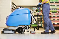 Worker cleaning floor with machine