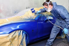 Worker painting a blue car.