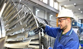 Workers manufacturing steam turbines in an industrial factory