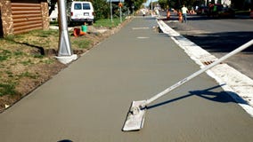 Workman finishes and smooths concrete surface on new sidewalk