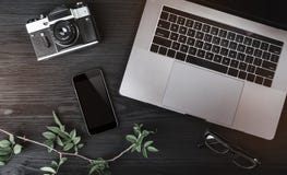 Workspace with notebook computer, phone, photo camera and eyeglasses on wooden texture table Royalty Free Stock Images Workspace with notebook computer, phone, photo camera and eyeglasses on wooden texture table Royalty Free Stock Images