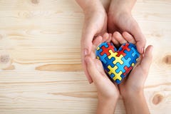World Autism Awareness day, puzzle or jigsaw pattern on heart with autistic child`s and women hands