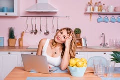 Worried and sad student female searching information in a laptop online sitting in the kitchen. Sad blonde woman feeling royalty free stock photography Worried and sad student female searching information in a laptop online sitting in the kitchen. Sad blonde woman feeling royalty free stock photography
