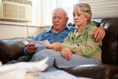 Worried Senior Couple Sitting On Sofa Looking At Bills stock photos Worried Senior Couple Sitting On Sofa Looking At Bills stock photos