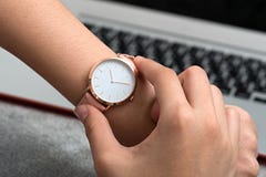 Wrist watch on girl`s hand in front of a desk with notebook comp royalty free stock images Wrist watch on girl`s hand in front of a desk with notebook comp royalty free stock images