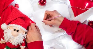 Write a letter with wishes on a white blanket. Write a wish list for Santa with a red pen on a blank white sheet. Red Christmas