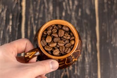 Wręcza trzymać filiżanka kawy fasole na czarnym ośniedziałym tle z miękkie ogniska, kosmos kopii obraz stock Wręcza trzymać filiżanka kawy fasole na czarnym ośniedziałym tle z miękkie ogniska, kosmos kopii obraz stock