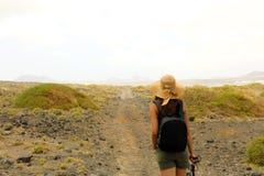 Wycieczkowicz kobiety rekonesansowy suchy region Lanzarote wyspa Młody żeński backpacker z słomianego kapeluszu odprowadzeniem w zdjęcia stock Wycieczkowicz kobiety rekonesansowy suchy region Lanzarote wyspa Młody żeński backpacker z słomianego kapeluszu odprowadzeniem w zdjęcia stock