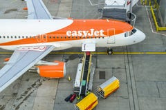 Wysoka perspektywa bagażowi podnosi up walizki od konwejeru paska łączył Aerobus A320 easyJet samolot przy Lonem zdjęcie stock Wysoka perspektywa bagażowi podnosi up walizki od konwejeru paska łączył Aerobus A320 easyJet samolot przy Lonem zdjęcie stock