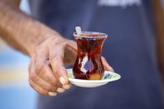 Wyśmienicie czerwona Turecka herbata z tradycyjna bonkreta kształtującym szkłem z teaspoon w mężczyzna ręce zdjęcia stock Wyśmienicie czerwona Turecka herbata z tradycyjna bonkreta kształtującym szkłem z teaspoon w mężczyzna ręce zdjęcia stock