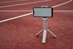 Wyśmiewa w górę czarnego smartphone z tripod Bielu ekran dla projekta szablonu na tle czerwony ślad dla zdjęcia royalty free Wyśmiewa w górę czarnego smartphone z tripod Bielu ekran dla projekta szablonu na tle czerwony ślad dla zdjęcia royalty free