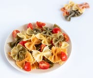 Włoszczyzna barwił makaronu farfalle z basilem i pomidorami na białym tle zdjęcia royalty free Włoszczyzna barwił makaronu farfalle z basilem i pomidorami na białym tle zdjęcia royalty free