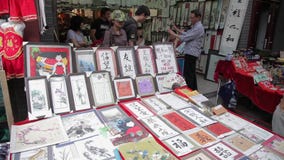 XIAN, CHINA - MAY 26, 2012: Unidentified people choose traditional souvenirs at the stall at the shopping street in Xian stock video footage XIAN, CHINA - MAY 26, 2012: Unidentified people choose traditional souvenirs at the stall at the shopping street in Xian stock video footage