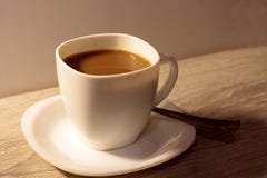 Xícara de café com leite em uma tabela de madeira foto de stock Xícara de café com leite em uma tabela de madeira foto de stock