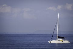 Yacht bianco del catamarano che naviga i mari blu calmi fotografia stock Yacht bianco del catamarano che naviga i mari blu calmi fotografia stock