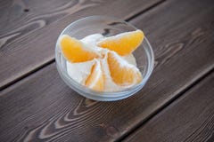 Yaourt et tranches oranges dans un plat en verre sur une table en bois Images stock Yaourt et tranches oranges dans un plat en verre sur une table en bois Images stock