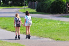 Yaslo Polen - juli 10 2018: Två flickor som rollerblading rymma händer aktiv livsstil Barn på sommarsemester Innegrej ch royaltyfri bild Yaslo Polen - juli 10 2018: Två flickor som rollerblading rymma händer aktiv livsstil Barn på sommarsemester Innegrej ch royaltyfri bild