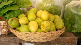 Yellow and green skin lemon in a brown basket, fresh organic lettuce vegetable in plastic bag on wooden table in a market royalty free stock image Yellow and green skin lemon in a brown basket, fresh organic lettuce vegetable in plastic bag on wooden table in a market royalty free stock image