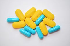 Yellow oval pills and blue capsules on white background top view closeup royalty free stock photos Yellow oval pills and blue capsules on white background top view closeup royalty free stock photos