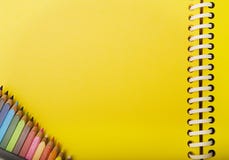 Yellow spring notebook and crayons in a corner.