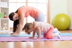 Yoga de pratique de fille de mère et d'enfant ensemble à la maison Sport et concept de la famille photos stock Yoga de pratique de fille de mère et d'enfant ensemble à la maison Sport et concept de la famille photos stock