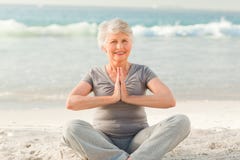 Yoga di pratica della donna maggiore sulla spiaggia fotografie stock libere da diritti Yoga di pratica della donna maggiore sulla spiaggia fotografie stock libere da diritti