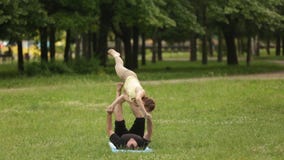 Yoga di pratica di acro delle belle coppie I giovani istruttori di yoga praticano in un parco della città su erba verde Due riusc archivi video Yoga di pratica di acro delle belle coppie I giovani istruttori di yoga praticano in un parco della città su erba verde Due riusc archivi video