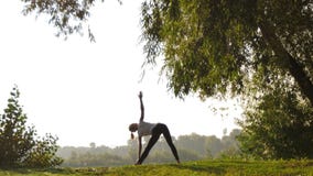 Yoga practicante de la mujer joven en la puesta del sol al aire libre almacen de metraje de vídeo Yoga practicante de la mujer joven en la puesta del sol al aire libre almacen de metraje de vídeo