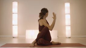 Woman doing seated spinal twist pose on mat. Fit girl performing yoga in studio