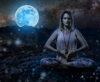 Yoga woman at night in the mountains. Woman yoga practitioner meditating during the moon ritual in the mountains, blue toned at midnight