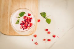 yogurt Iogurte com grandada e hortel? no vidro em uma bandeja de madeira e nas sementes dispersadas da rom? em uma tabela branca fotografia de stock yogurt Iogurte com grandada e hortel? no vidro em uma bandeja de madeira e nas sementes dispersadas da rom? em uma tabela branca fotografia de stock