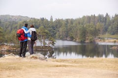Young adult couple standing on a rock admiring the lakeside view, back view stock images Young adult couple standing on a rock admiring the lakeside view, back view stock images