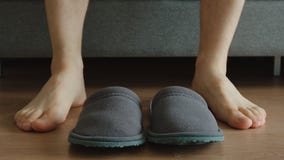 Young adult man sits on a sofa near a slippers - feet level Stock Photo Young adult man sits on a sofa near a slippers - feet level Stock Photo