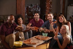 Young adults eating pizza at a party look to camera stock photography Young adults eating pizza at a party look to camera stock photography