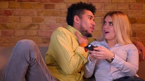 Young african guy with his blonde caucasian girlfriend watching horror movie on TV in cozy home atmosphere. stock video Young african guy with his blonde caucasian girlfriend watching horror movie on TV in cozy home atmosphere. stock video
