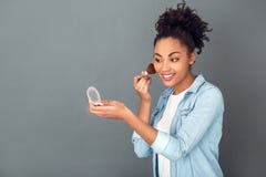 Young african woman isolated on grey wall studio casual daily lifestyle doing makeup royalty free stock image Young african woman isolated on grey wall studio casual daily lifestyle doing makeup royalty free stock image