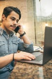 Young Arabian Businessman Working In Cafe Using Phone And Computer. Modern Big City Lifestyle Royalty Free Stock Photos Young Arabian Businessman Working In Cafe Using Phone And Computer. Modern Big City Lifestyle Royalty Free Stock Photos